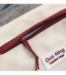 Macrodetail van beige canvas tas met bordeauxrode rits en geweven trekker aan de zijde