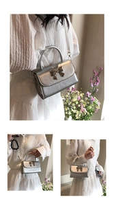 Detail of silver metallic handbag with a glossy bow accent and sleek round handle