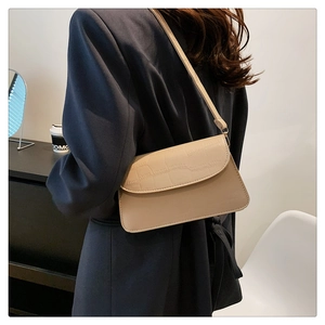 Detail of minimalist beige shoulder bag showing crocodile texture and smooth leather finish