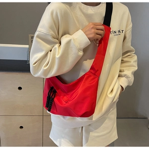 Detail of red crescent crossbody bag with black wide strap and dual woven zip pullers