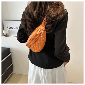 Detailed back view of a bright orange quilted nylon crossbody bag worn on a model