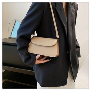 Minimalist beige faux leather shoulder bag styled on a black blazer with sleek strap