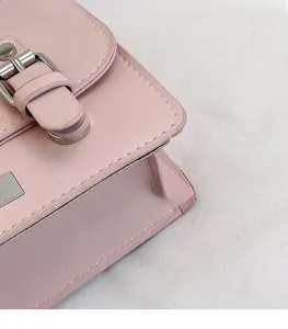 Detail view of pink satchel with white stitching and vintage metal buckle closure
