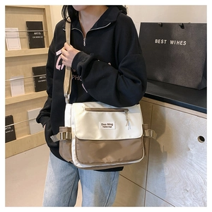 Détail du sac messager en toile contrastée avec boucles réglables et poche zippée à l'avant