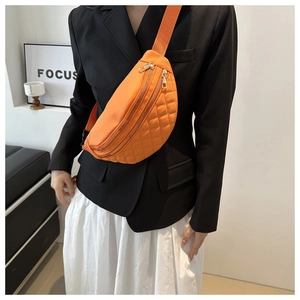 Detail of orange quilted chest bag with dual gold zippers and adjustable wide strap