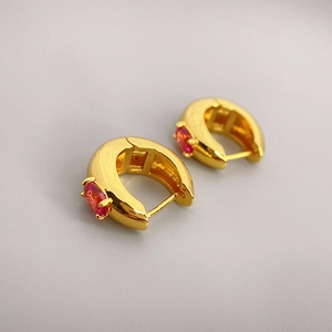 Detail of 18K gold plated earrings with oval red zircon and polished hollow structure