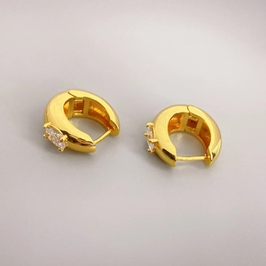 Detailed close-up of gold-plated huggie earrings with marquise-cut green zircon inlay