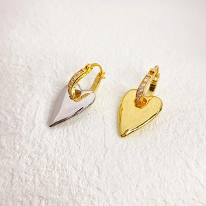Modern 18K gold plated brass heart earrings with zircon studs shown on white texture