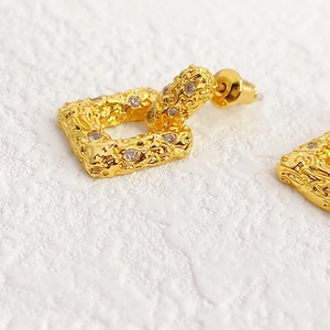 Chic gold lava-textured square earrings with diamonds on a minimalist white stone surface
