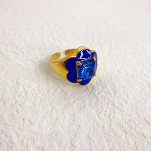 Détail de la bague dorée avec trèfle en émail bleu et pierre précieuse carrée