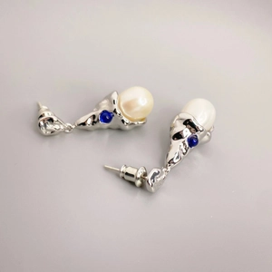 Modern silver liquid metal earrings with large white pearl and blue gemstone accents