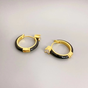 Détail macro de boucles d'oreilles en émail noir avec zircon carré et placage d'or 18K