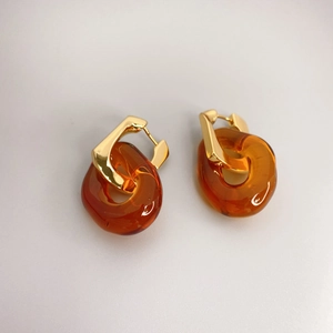 Détail de boucles d'oreilles dorées en U avec pendentifs en résine ambrée