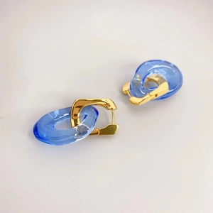Boucles d'oreilles dorées en U avec anneaux en résine bleue présentées à plat de haut