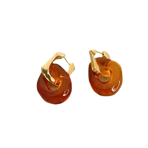Boucles d'oreilles en U plaquées or avec pendentifs en résine ambre sur fond blanc