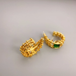 Golden C-shaped hoop earrings with woven texture and a square green emerald gemstone
