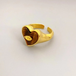 Makroansicht des goldenen Herzrings mit eingelegtem Tigerauge und zentralem Augen-Design