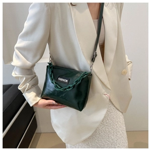Detail of dark green chain shoulder bag styled with a white blazer and skirt