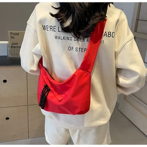 Detail einer roten Nylon-Umhängetasche mit breitem Schultergurt, von einem Model getragen