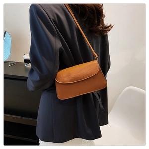 Detail of elegant brown faux crocodile leather shoulder bag on female model in blazer