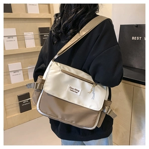 Detailopname van contrast canvas schoudertas met merklabel en verstelbare riem
