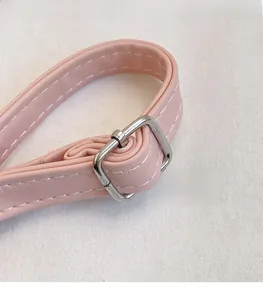 Detail of pink faux leather strap with silver buckle and white stitching craftsmanship