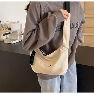 Detail of cream white crescent bag with black woven zipper pull and nylon texture