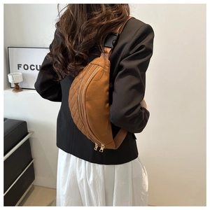 Detail of caramel nylon belt bag with quilted pattern, gold zipper and adjustable strap