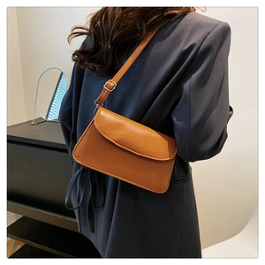 Detail view of caramel crocodile pattern leather bag with adjustable golden buckle strap