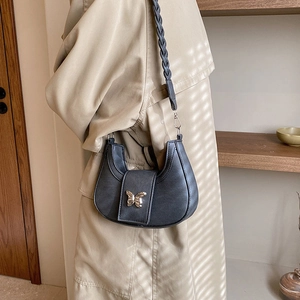 Women's black crescent shoulder bag with golden butterfly buckle and woven strap detail
