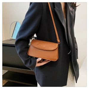 Close-up of brown crocodile pattern leather shoulder bag with gold metal hardware detailing