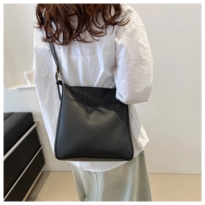Minimalist black square crossbody bucket bag with adjustable strap on model back view