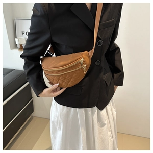 Close-up of brown quilted nylon saddle bag worn crossbody on a modern blazer outfit
