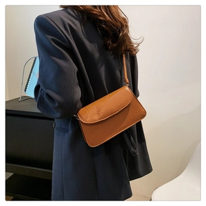 Close-up of brown crocodile texture leather crossbody bag styled with navy blazer