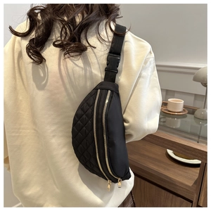 Rear view of black quilted nylon crossbody bag with adjustable strap in cafe setting