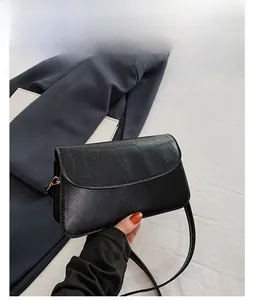 Detail of black crossbody bag with faux crocodile pattern and golden hardware
