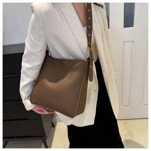 Detail of dark brown matte leather bucket bag with eyelet strap on model