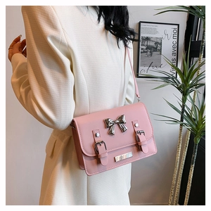 Pink crossbody bag detail featuring a silver metal bow and buckle straps on white suit