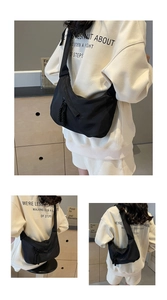 Detail of black crescent shoulder bag featuring a unique braided tassel zipper puller