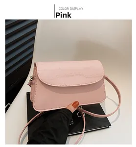 Close-up of pink square bag showing faux crocodile texture and gold hardware details