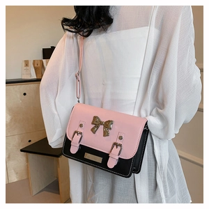 Detail of pink and black crossbody bag with metal bow buckle and synthetic leather finish