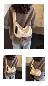Detail view of a cream-colored half-moon tote bag with a unique woven zipper puller