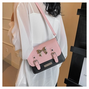 Detail of pink and black crossbody bag with metal bow and double buckle straps