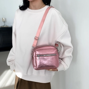 Pink iridescent metallic crossbody bag with adjustable strap and front zipper detail