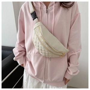 Detail of quilted fanny pack with gold zipper and adjustable strap worn by model