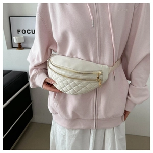 Detail of cream quilted nylon saddle bag showing dual gold zippers and shoulder strap