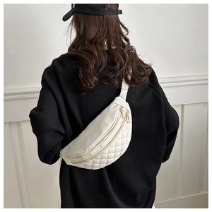 Close-up of beige quilted nylon crossbody bag showing dual gold zippers and texture