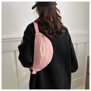 Pink quilted nylon fanny pack worn as a crossbody bag with dual golden zippers