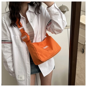 Détail du sac cabas en toile orange avec petit porte-monnaie rond et étiquette mode