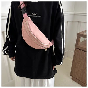 Close-up of pink crossbody bag with quilted rhombic patterns and double golden zippers